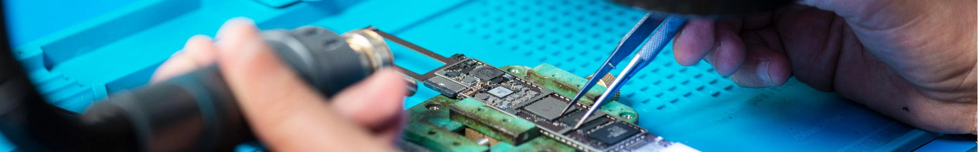 Dettaglio di un circuito stampato con mani di tecnico al lavoro, simbolo di precisione in laboratorio elettronico